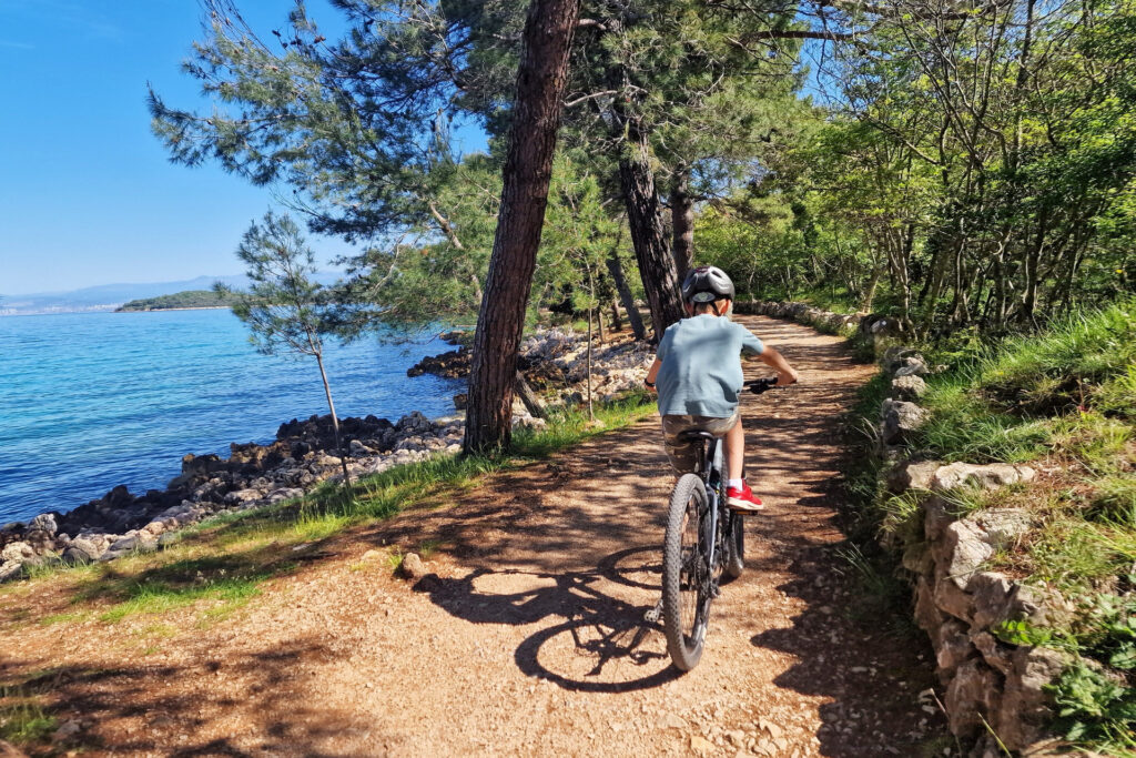 Kid riding a bike on a trail next to the sea